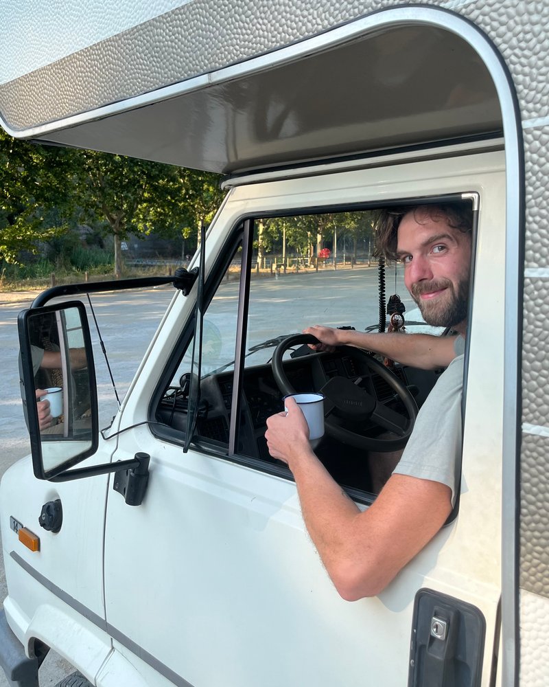 Tsjerk with a cup of coffee behind the wheel of his camper